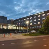 Hotel Kopernik Olsztyn z neonowym napisem "RESTAURACJA" i oświetlonymi oknami. Zapraszamy na nocleg i pyszne jedzenie.