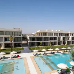 Nowoczesne budynki hotelowe Rixos z basenami i leżakami pod palmami.