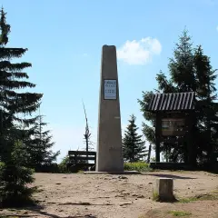 Szczyt Turbacz, 1310 m n.p.m. – ile się idzie? Widok na obelisk, krzyż i tablice informacyjne w otoczeniu górskich lasów.