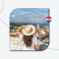 Kobieta w kapeluszu podziwia widok na chorwackie miasto. Czy do Chorwacji potrzebny jest paszport? Dowiedz się, planując podróż.