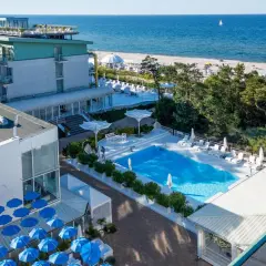 Nowoczesny hotel nad samym morzem z basenem i leżakami. Widok na plażę i błękitne morze.