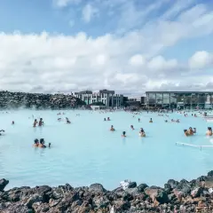 Ludzie kąpią się w turkusowej wodzie geotermalnego **blue lagoon** otoczonej wulkanicznymi skałami.