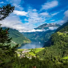 Widok na fiord podczas wycieczki do Norwegii. Statek wycieczkowy wpływa do malowniczej doliny otoczonej zielonymi górami.