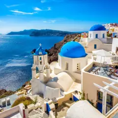 Białe domy z niebieskimi kopułami na tle morza. Widok na Santorini, jedne z najpiękniejszych wysp greckich.