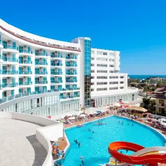 Hotel Narsia Resort: biały, nowoczesny budynek z niebieskimi balkonami i basenem z atrakcjami wodnymi. Słoneczny dzień, wakacyjna atmosfera.
