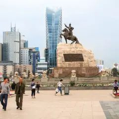 Pomnik Czyngis-chana na placu w Ułan Bator, stolicy Mongolii, z nowoczesnymi wieżowcami w tle.