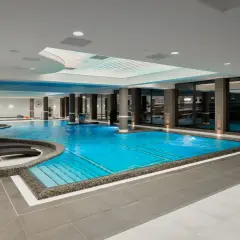 Luksusowy basen w Evita Hotel Spa z błękitną wodą, leżakami i kaskadą. Idealne miejsce na relaks.