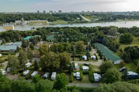 Malta hotel camping: kampery i przyczepy kempingowe wśród zieleni, z widokiem na jezioro i miasto w tle.