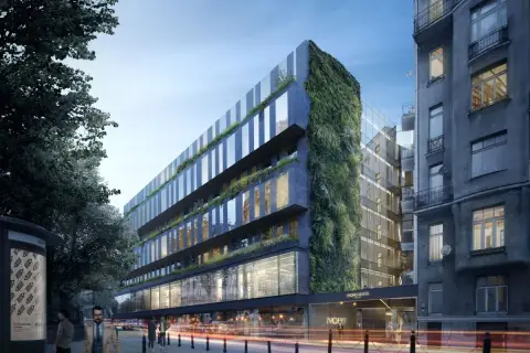 Nowoczesny hotel Nobu Warszawa z zieloną ścianą i przeszklonymi fasadami, otoczony miejską zabudową i drzewami.