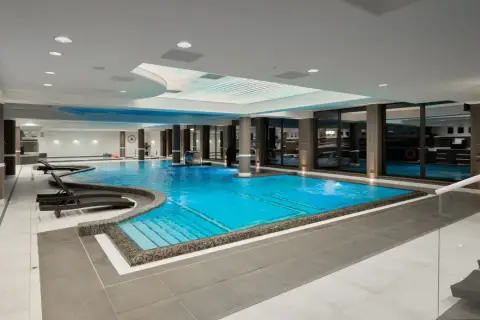Luksusowy basen w Evita Hotel Spa z błękitną wodą, leżakami i kaskadą. Idealne miejsce na relaks.