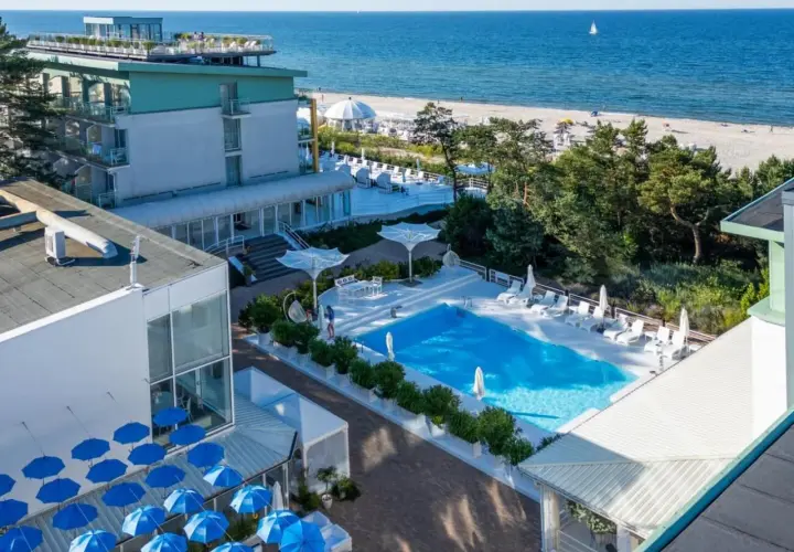 Nowoczesny hotel nad samym morzem z basenem i leżakami. Widok na plażę i błękitne morze.