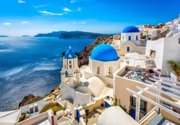 Białe domy z niebieskimi kopułami na tle morza. Widok na Santorini, jedne z najpiękniejszych wysp greckich.