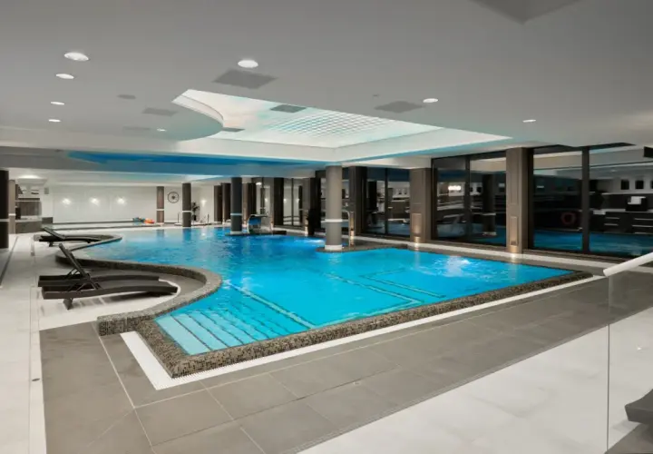 Luksusowy basen w Evita Hotel Spa z błękitną wodą, leżakami i kaskadą. Idealne miejsce na relaks.