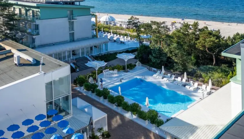 Nowoczesny hotel nad samym morzem z basenem i leżakami. Widok na plażę i błękitne morze.