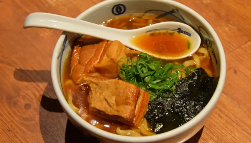 Pyszne japońskie jedzenie: miska ramenu z kawałkami wieprzowiny, szczypiorkiem i wodorostami nori.