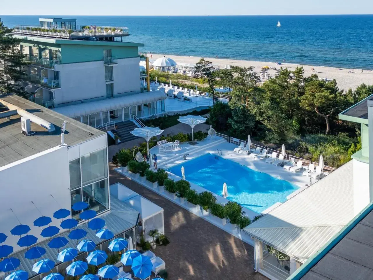 Nowoczesny hotel nad samym morzem z basenem i leżakami. Widok na plażę i błękitne morze.