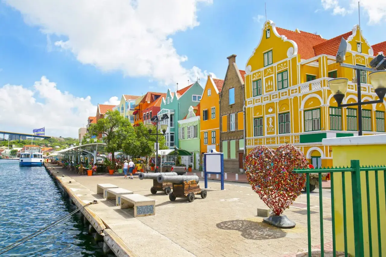 Kolorowe budynki, serce z kłódek i armaty nad wodą – idealne miejsce na curacao wakacje.