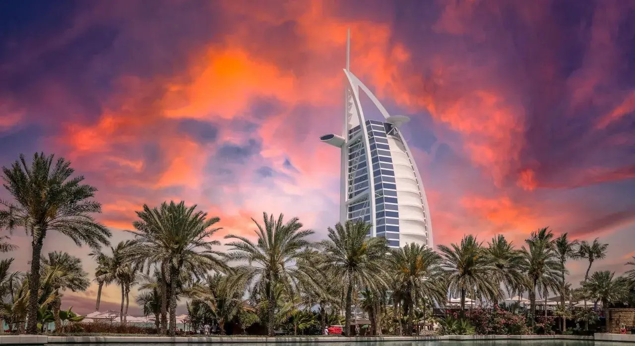 Zachód słońca nad Dubajem, palmy i hotel Burdż al-Arab. Zastanawiasz się, ile kosztuje wycieczka do Dubaju?