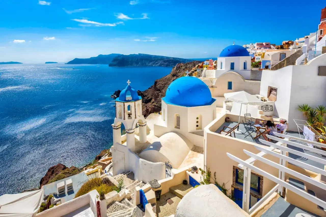 Białe domy z niebieskimi kopułami na tle morza. Widok na Santorini, jedne z najpiękniejszych wysp greckich.