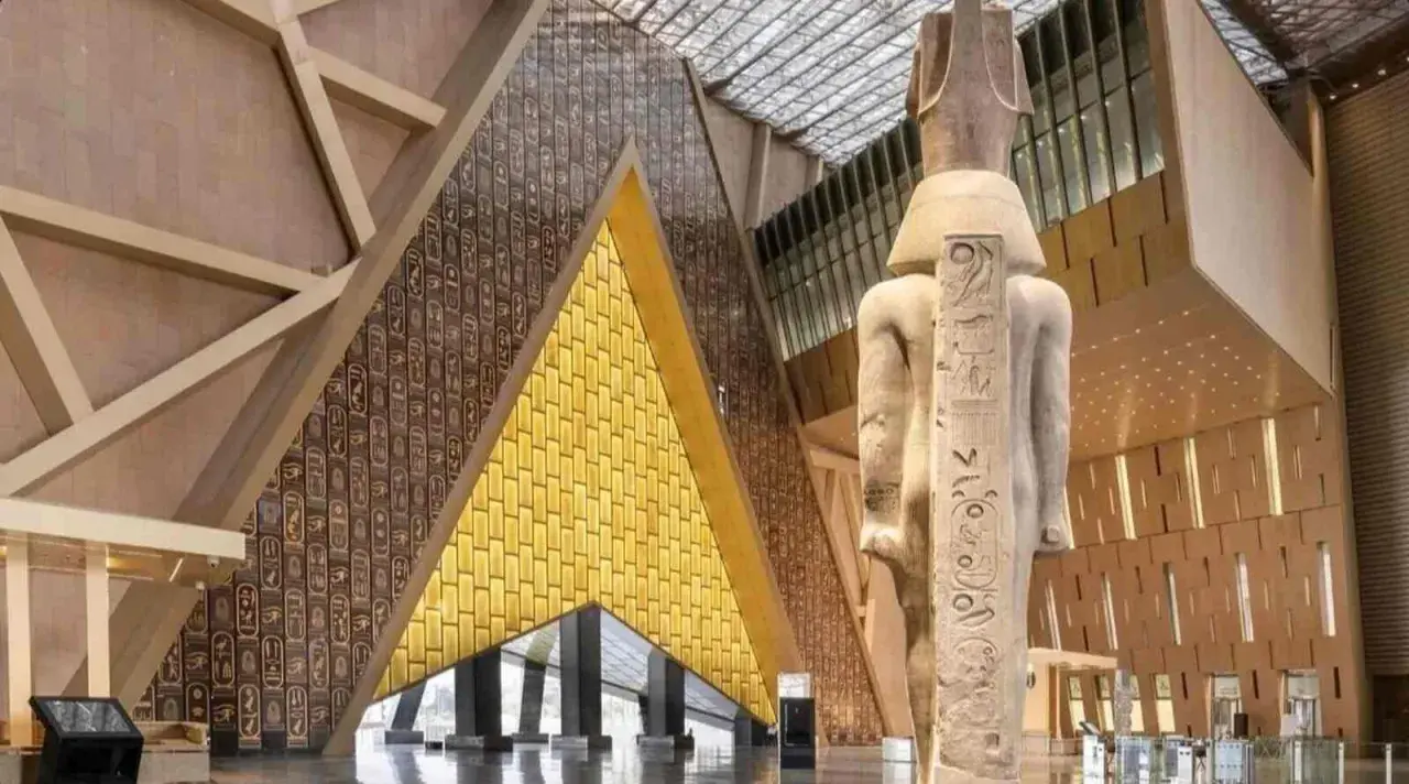 Wielki posąg faraona w nowoczesnym wnętrzu nowego muzeum w Egipcie. Ściany zdobią hieroglify i złote panele.