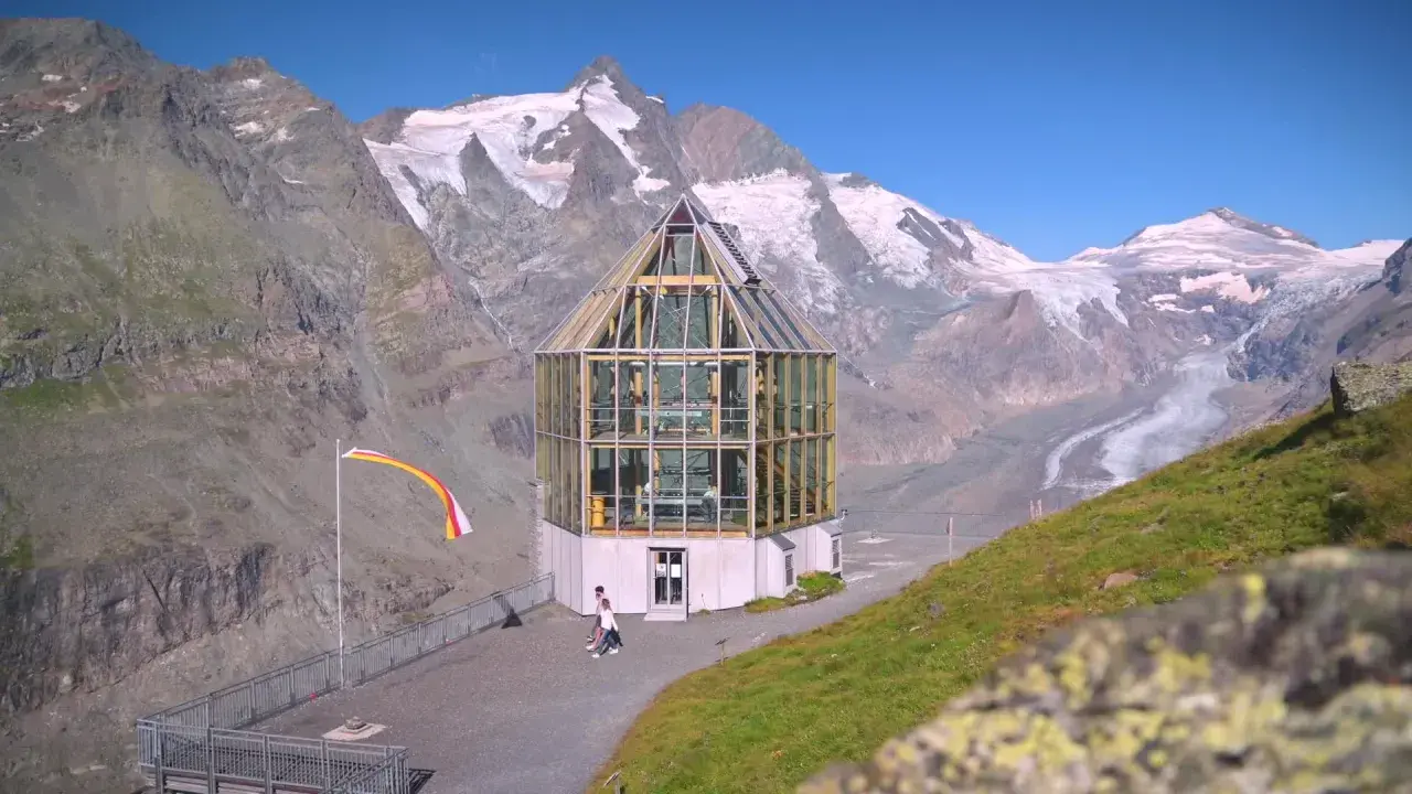 Szklana budowla na tle najwyższego szczytu Austrii, Grossglockner. Lodowiec w oddali.