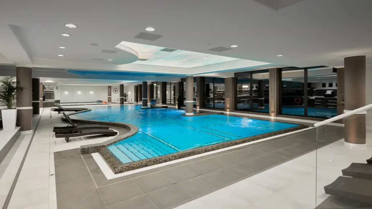 Luksusowy basen w Evita Hotel Spa z błękitną wodą, leżakami i kaskadą. Idealne miejsce na relaks.