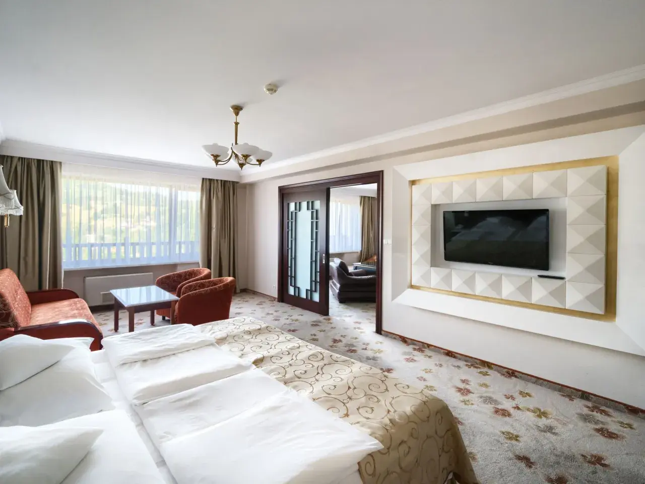 Pokój w hotelu Gołębiewski Wisła: łóżko, kanapa, fotele, stolik i TV.