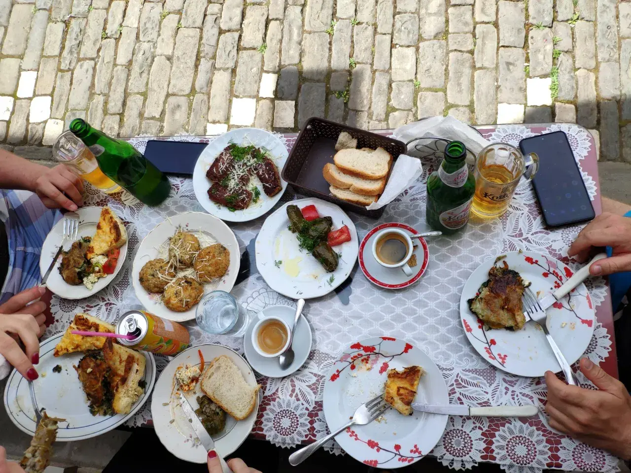 Pyszne albania jedzenie na stole: mięso, gołąbki, pieczywo, kawa i piwo.