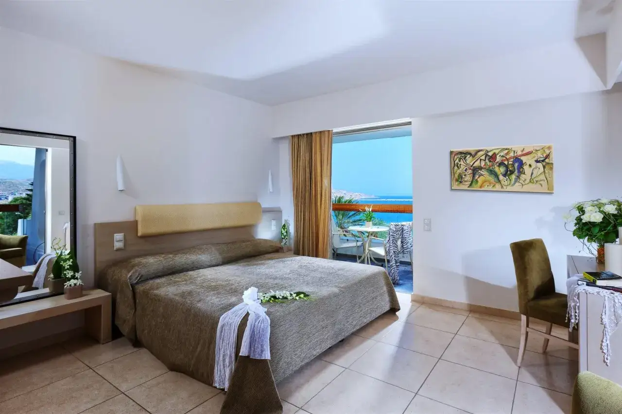 Pokój w hotelu Narcia Resort z widokiem na morze. Duże łóżko, balkon z stolikiem i krzesłami.