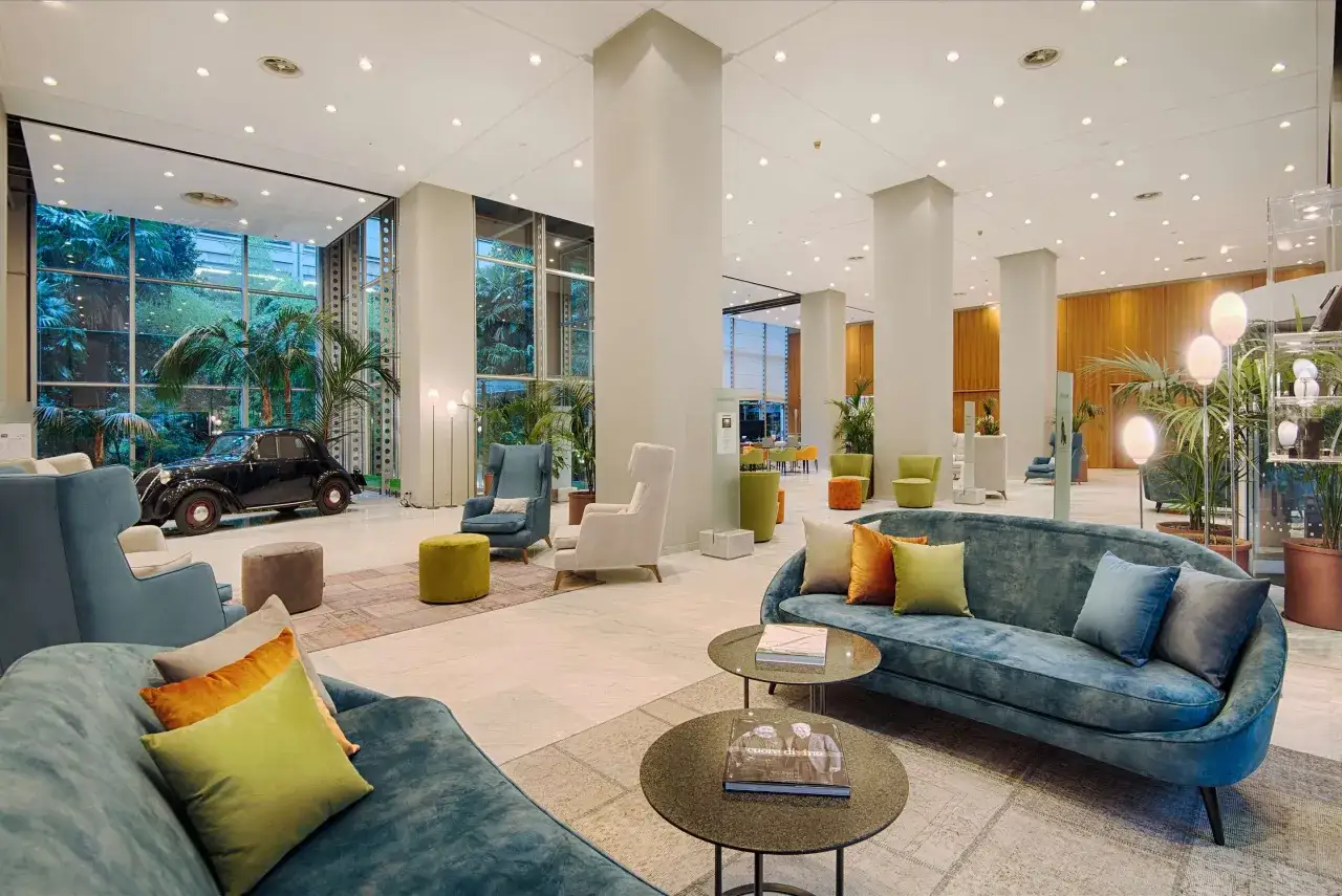 Eleganckie wnętrze hotelu Torino z wygodnymi sofami, fotelami i stylowym, zabytkowym samochodem.