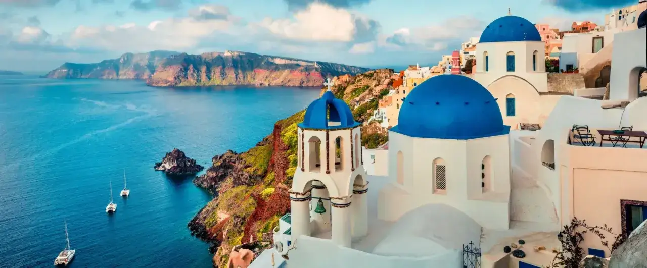 Santorini, jedno z najpiękniejszych wysp greckich, z białymi domkami i niebieskimi kopułami kościołów na tle kalderry.