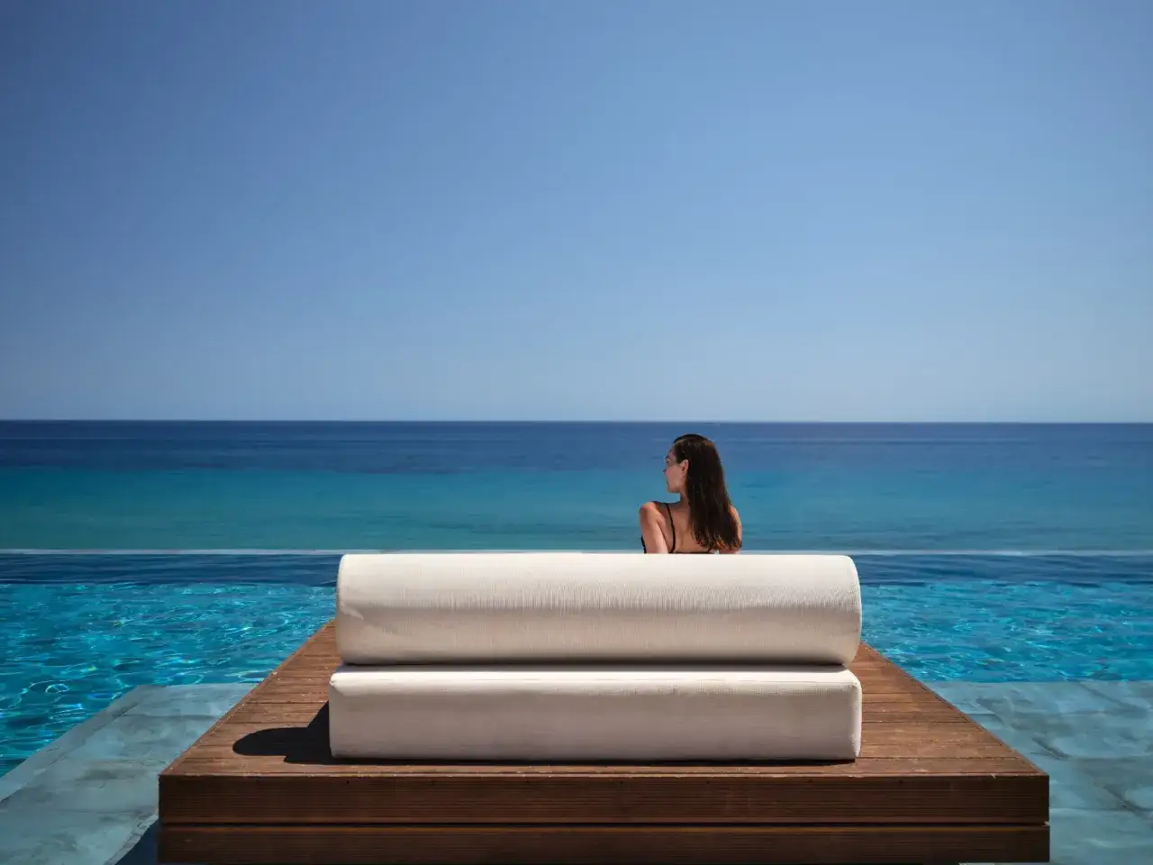 Kobieta wpatrzona w bezkresne morze z tarasu przy basenie. Idealny relaks w Tragaki Zakynthos.