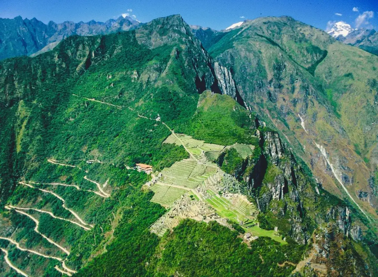 Niesamowita Machu Picchu wycieczka z lotu ptaka. Kręta droga prowadzi do starożytnego miasta Inków, otoczonego zielonymi górami.